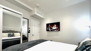 Een moderne hotelkamer met een bed, een aan de muur bevestigde televisie, een garderobe en een deur.