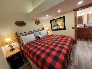 A bedroom with a bed, a nightstand, a lamp, a mirror, and a wooden headboard.