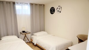Une chambre avec deux lits simples, une table de chevet avec une lampe et une chaise.