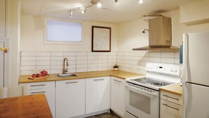 Une cuisine avec des armoires blanches, une cuisinière, un évier et une fenêtre.