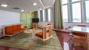 En moderne stue med sofa, et lille bord, et fjernsyn og et spiseområde med stole og et bord.