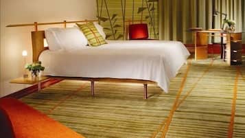 A modern hotel room with a large bed, a desk, and a red sofa.