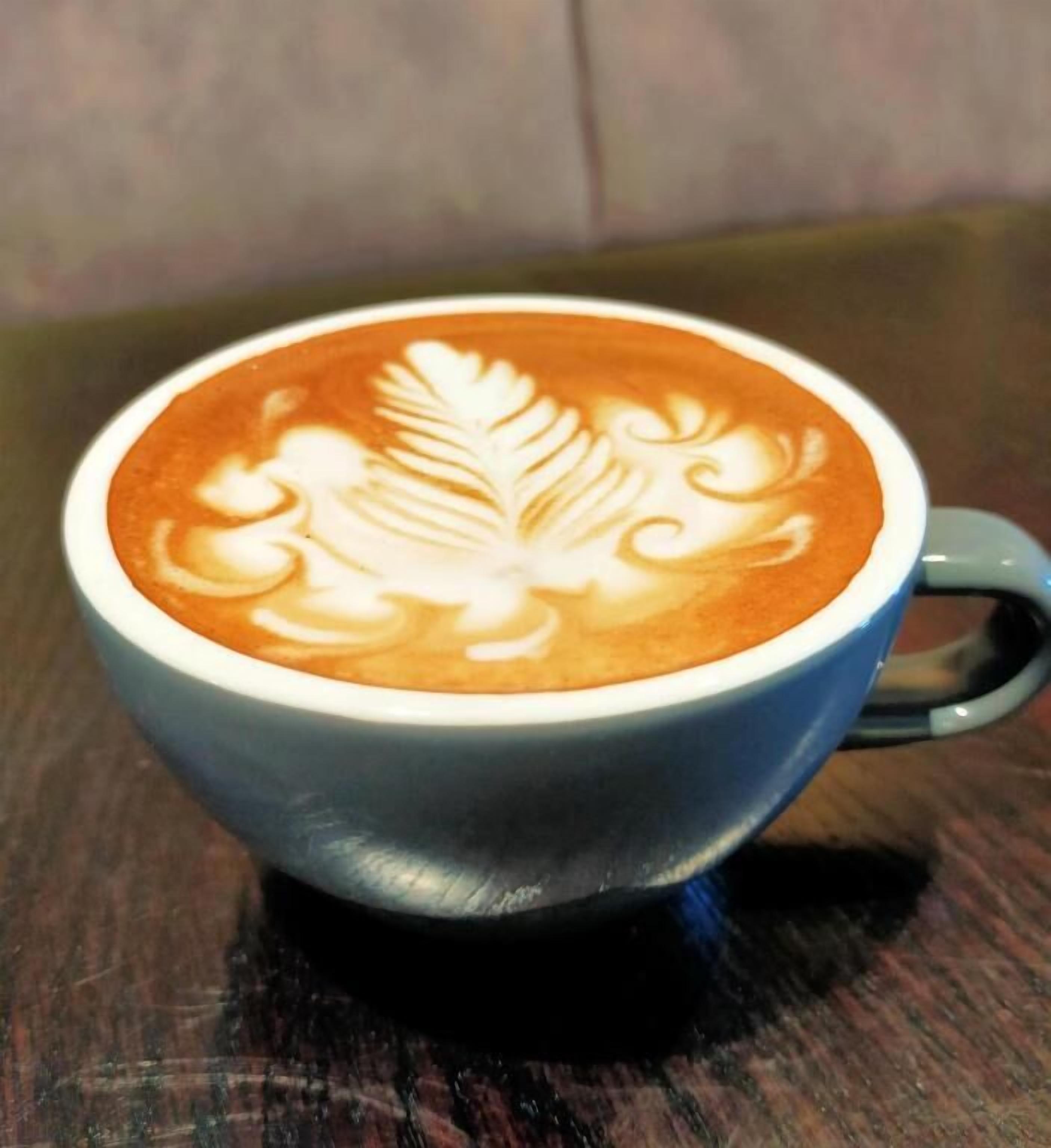 A cup of coffee with latte art on a wooden table.