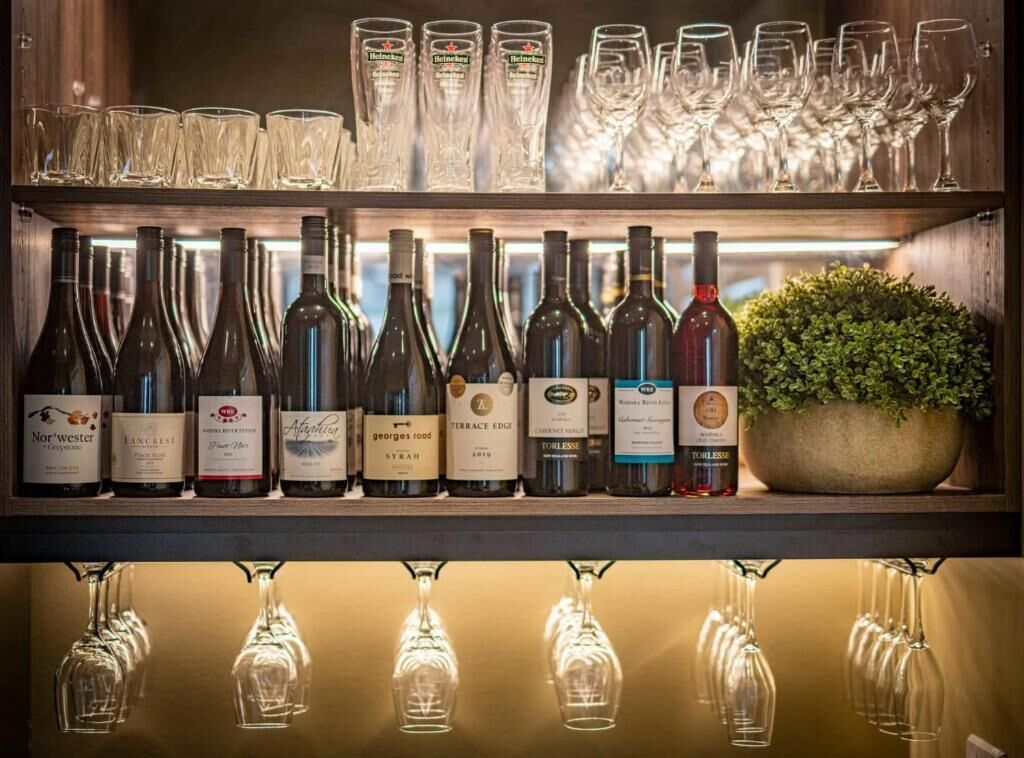 Un espace bar avec des étagères remplies de bouteilles de vin et de verres.
