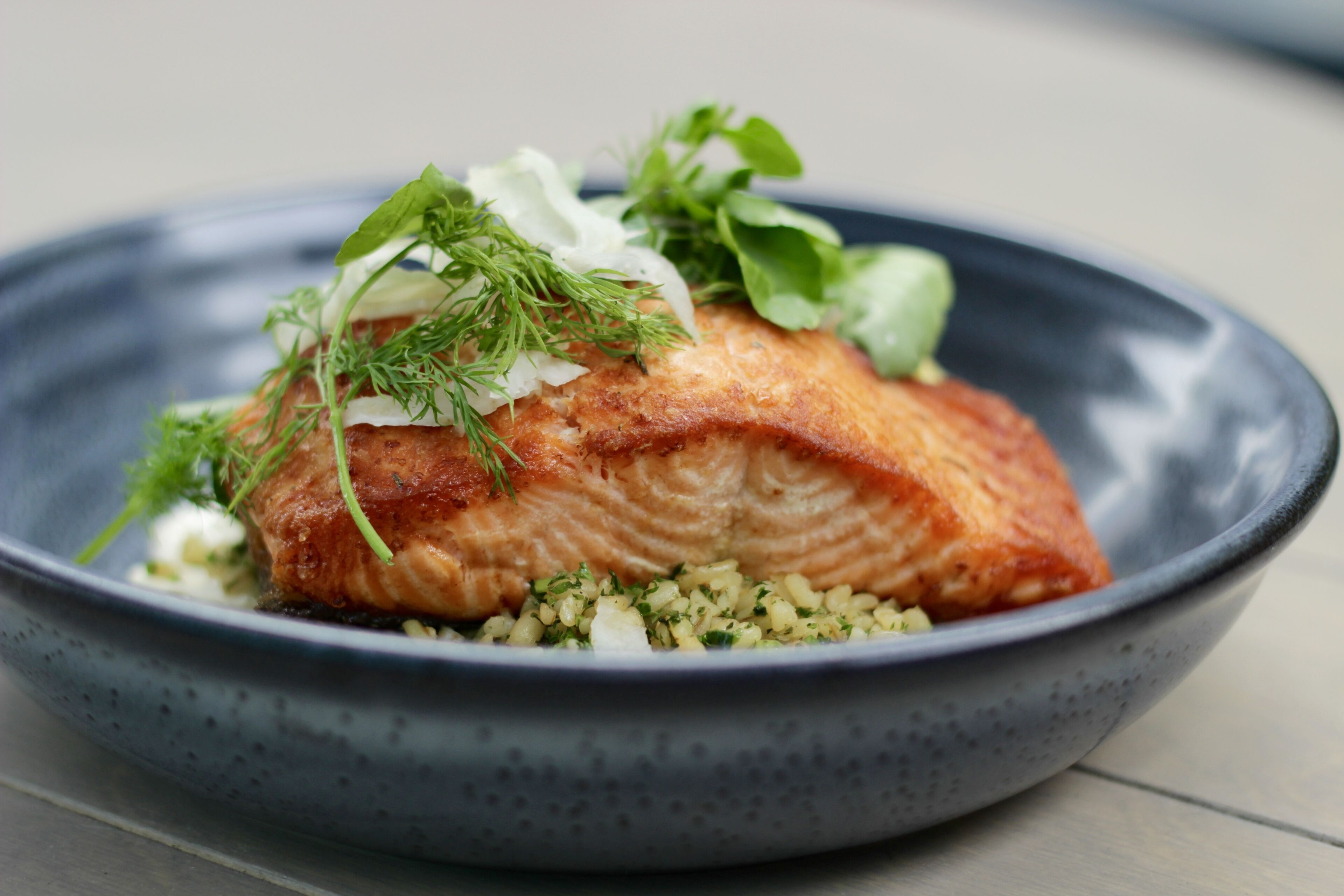 A plate of salmon with greens and a creamy sauce.