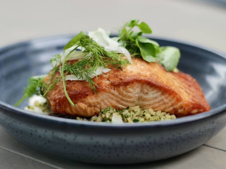 A plate of salmon with greens and a creamy sauce.