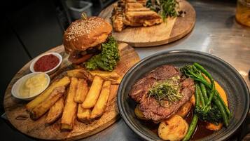A meal with a burger, fries, and a steak with vegetables.