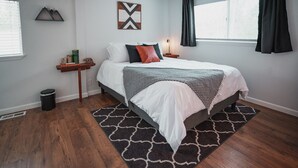 A bedroom with a bed, a nightstand, a wall-mounted shelf, and a window with curtains. - Harte Of The Pines Pet Friendly Walk to Downtown (Twain Harte)