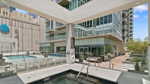 Een modern dakzwembad met glazen balustrades, een bordje voor de spa en uitzicht op wolkenkrabbers.