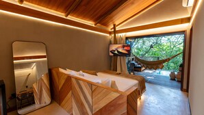 Een moderne badkamer met een houten wastafelmeubel, een grote spiegel en een televisie.