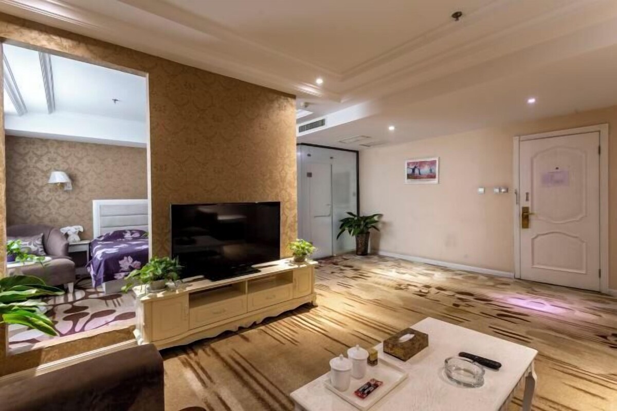 A modern living room with a flat-screen TV, a sofa, a coffee table, and a large mirror.