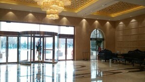 Un hall d’entrée doté d’une porte tournante, d’un lustre et d’un espace détente avec des canapés.