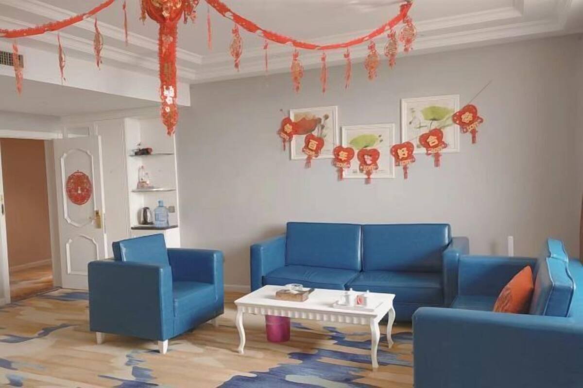 A living room with blue sofas, a white coffee table, and red decorations on the wall.