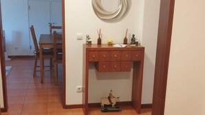 A room with a wooden desk, a blue rug, and a wall-mounted circular mirror.