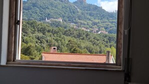 A view from a window overlooking a hillside with a castle-like structure and scattered houses.