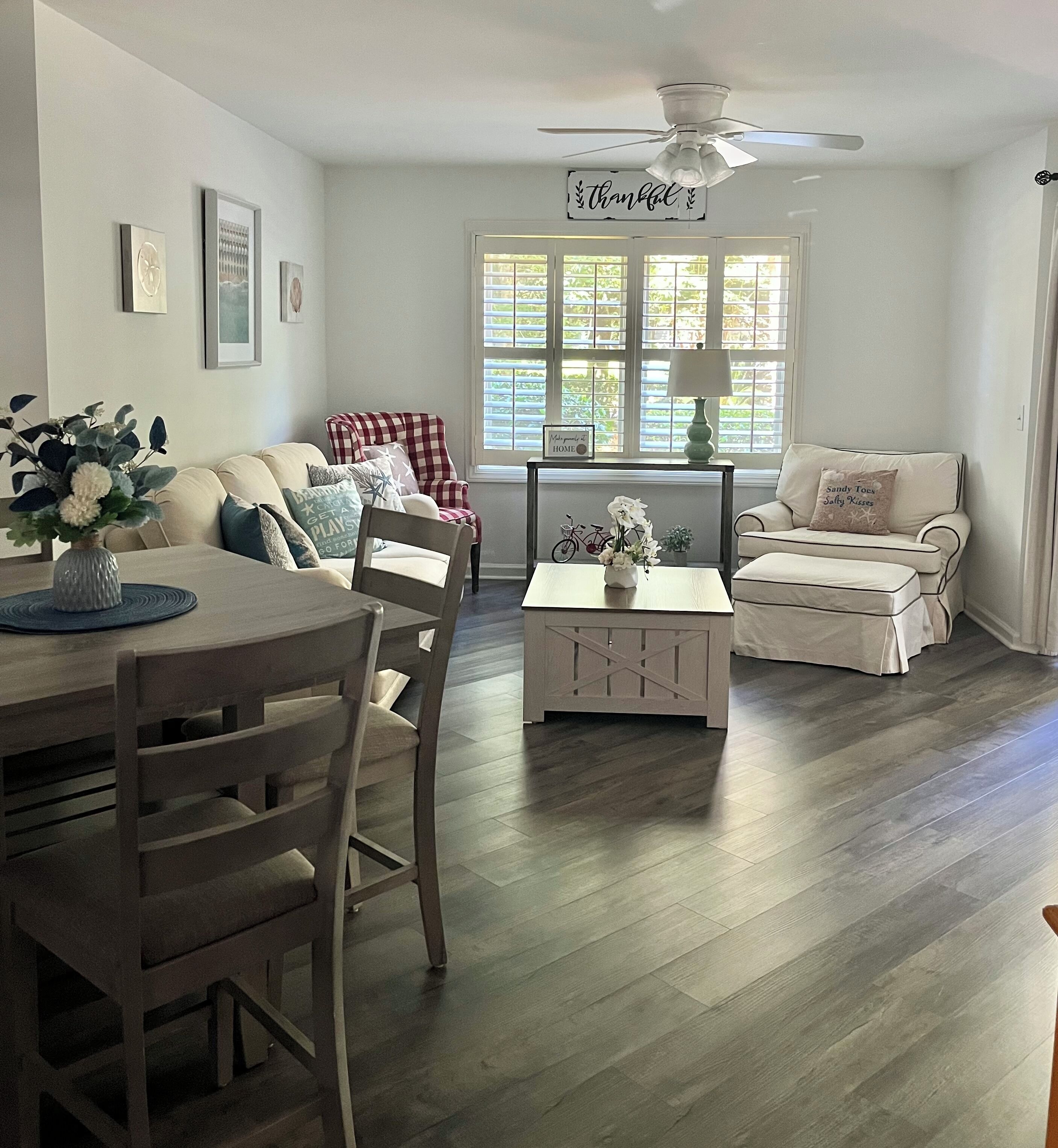 A living room with a dining table, two sofas, a chair, and a ceiling fan.