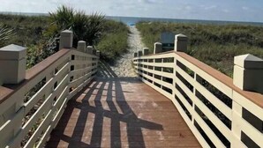 Un muelle de madera que conduce a una playa bajo un cielo despejado.