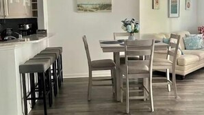 Una sala de estar moderna con comedor, ventilador de techo y cocina al fondo.