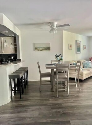 Un soggiorno moderno con zona pranzo, ventilatore a soffitto e cucina sullo sfondo.