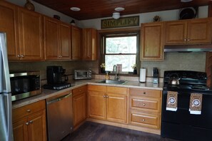 A kitchen with wooden cabinets, a microwave, a coffee maker, a toaster, a sink, and a stove. - Poconos Top Rated Resort - Saw Creek Estates (Bushkill)