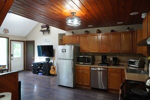 A kitchen with wooden cabinets, a stainless steel refrigerator, a microwave, a coffee maker, and a toaster.
