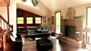 A living room with a fireplace, a black leather sofa, and a wooden coffee table. - Poconos Top Rated Resort - Saw Creek Estates (Bushkill)