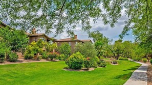 A residential property with a well-maintained lawn, a pathway, and a variety of trees and shrubs.