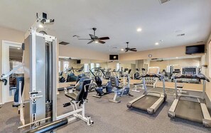 Un gimnasio con varios equipos de ejercicio, como cintas de correr, bicicletas estáticas y máquinas de pesas.