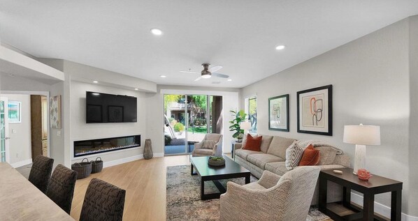 Una sala de estar moderna con chimenea, televisor y zona de estar con mesa de centro y sillas.