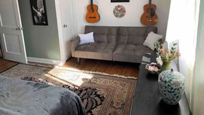 A cozy living room with a grey sofa, two guitars, a framed picture, and a decorative vase. - Lancaster Musically Inspired Home Downtown Sleeps6 (Lancaster)