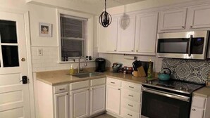 A modern kitchen with white cabinets, stainless steel appliances, and a tiled backsplash. - Lancaster Musically Inspired Home Downtown Sleeps6 (Lancaster)
