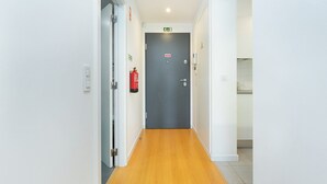 Een gang met een houten vloer, witte muren en een grijze deur aan het einde.