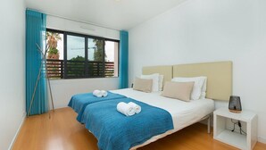 Een moderne slaapkamer met een groot bed, twee nachtkastjes en een raam met gordijnen.