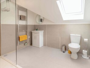 A modern bathroom with a glass shower enclosure, a white sink, a toilet, and a mirror.