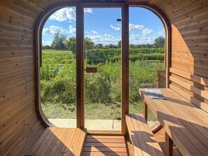 A wooden room with a large circular window, a wooden bench, and a table with a magazine.