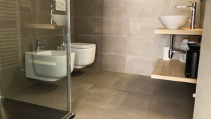 Un baño moderno con cabina de ducha de vidrio, un lavamanos blanco y un inodoro.