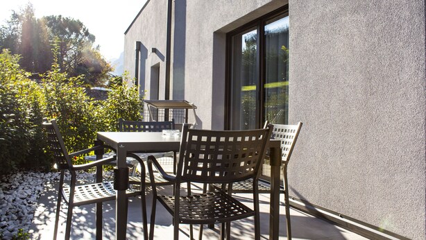 Un patio al aire libre con mesa y sillas, un camino de piedra y un edificio con ventanas grandes.