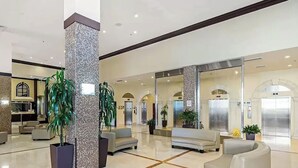 A spacious lobby with a high ceiling, a central column, and seating areas. - Oceanfront renovated condo on the beach - amazing ocean view (Sunny Isles Beach)