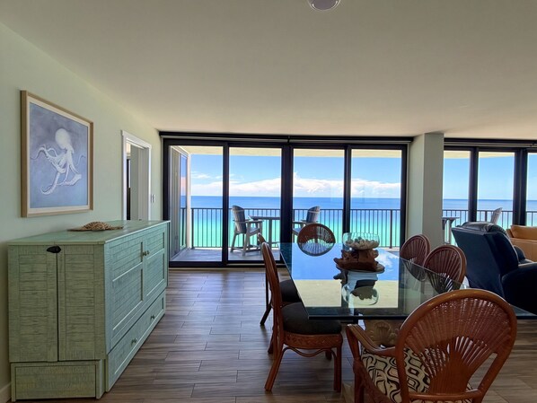 A dining area with a view of the ocean, a large window, and a dining table with chairs.