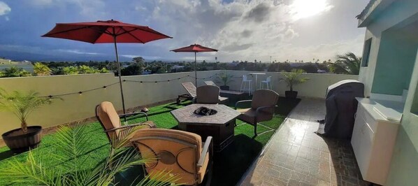 A rooftop patio with a table and chairs, a barbecue grill, and potted plants. - 5 pools, Amazing Rooftop Views , Beach (Vieques)