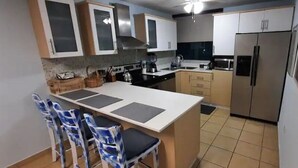 A kitchen with a central island, bar stools, and a refrigerator. - 5 pools, Amazing Rooftop Views , Beach (Vieques)