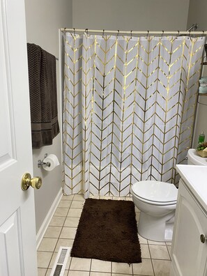 A bathroom with a shower curtain, toilet, and a brown rug on the floor. - The NashvilleNest 3BR 2Ba Large Fenced Yard 15 Min to DT (Nashville)