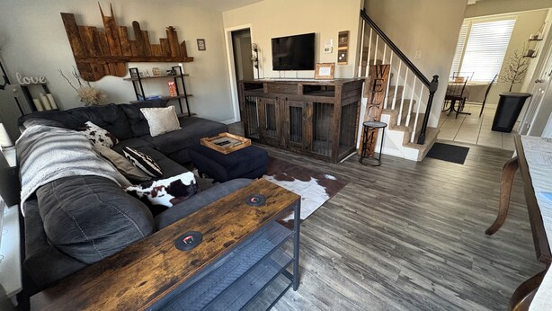 Un salon moderne avec un canapé d’angle gris foncé, une table basse en bois et un mur décoratif en bois au style rustique.