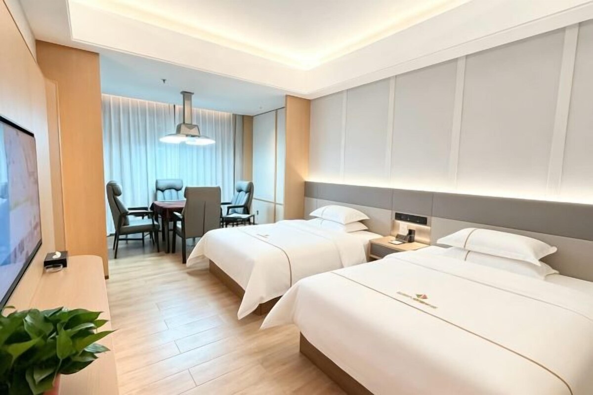 Habitación de hotel con dos camas, un escritorio y una silla.