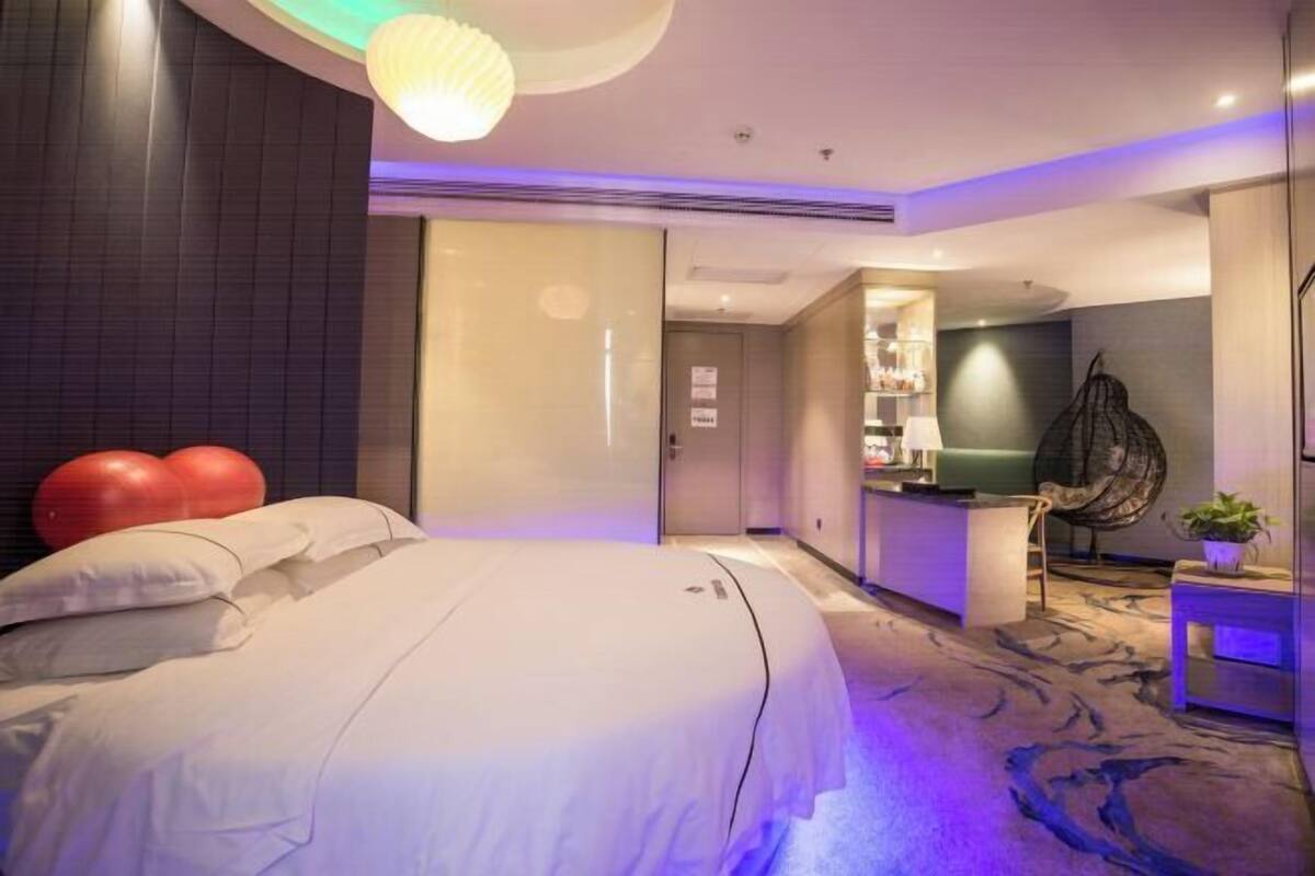 Habitación de hotel con una cama grande, un escritorio, una silla y una mesita con una planta.