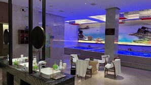 A modern bathroom with a large mirror, a marble countertop, and a seating area with chairs and a small table. - Huarong Hongfa International Hotel (People's Square) (Huarong)