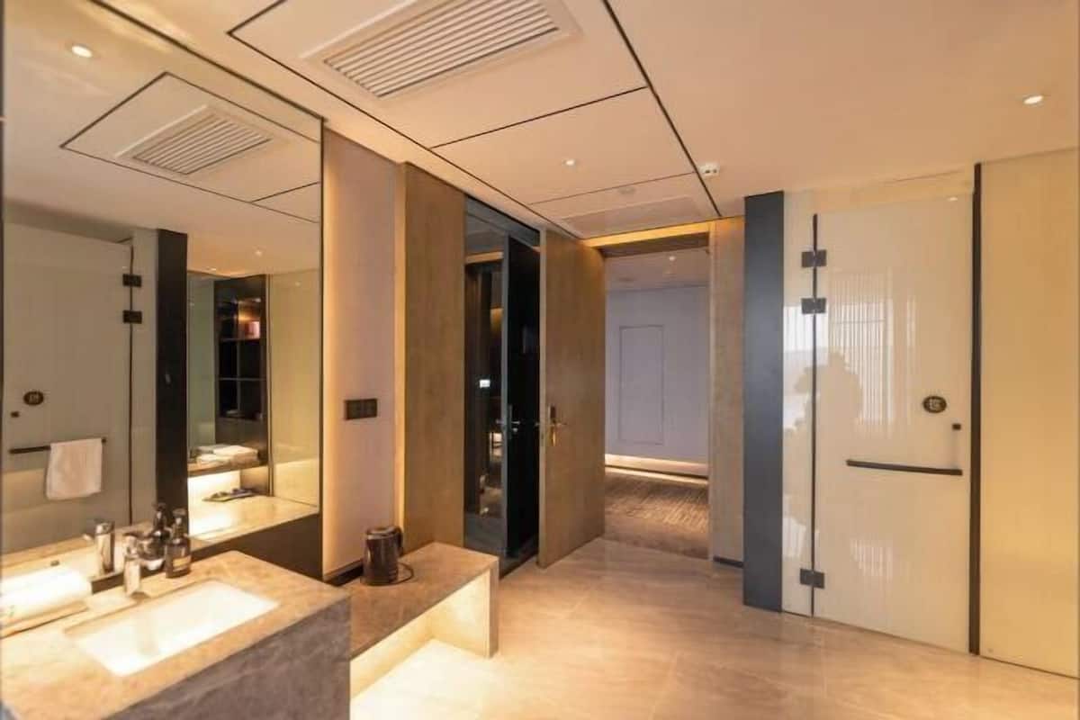 A modern bathroom with a large mirror, a sink, and a door leading to another room.