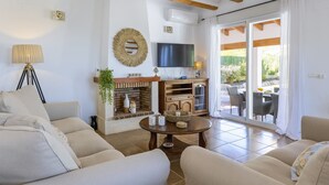 A living room with sofas, a TV, a fireplace, and a dining area with outdoor seating. - Casa de los Sueños (Javea / Xàbia)