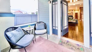 A balcony with two chairs, a small table, and a welcome mat.