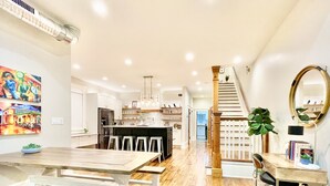 A modern kitchen with a central island, bar stools, and a staircase leading to another level.